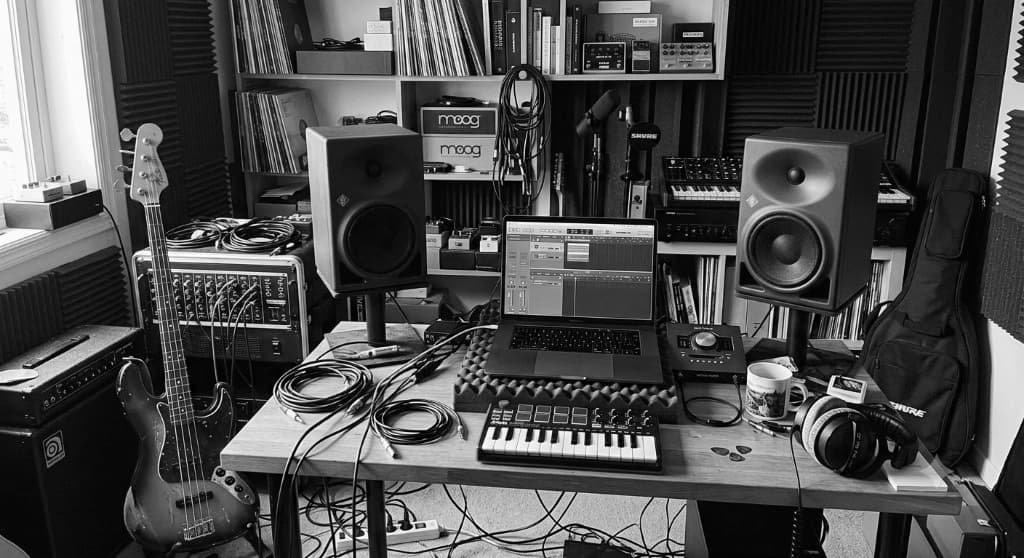 Music Production Studio Workspace with Laptop DAW, Monitors, Synthesizer and Bass Guitar